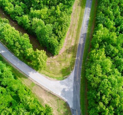 Aerial view of two roads intersecting in a green forest area.