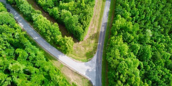 Aerial view of two roads intersecting in a green forest area.